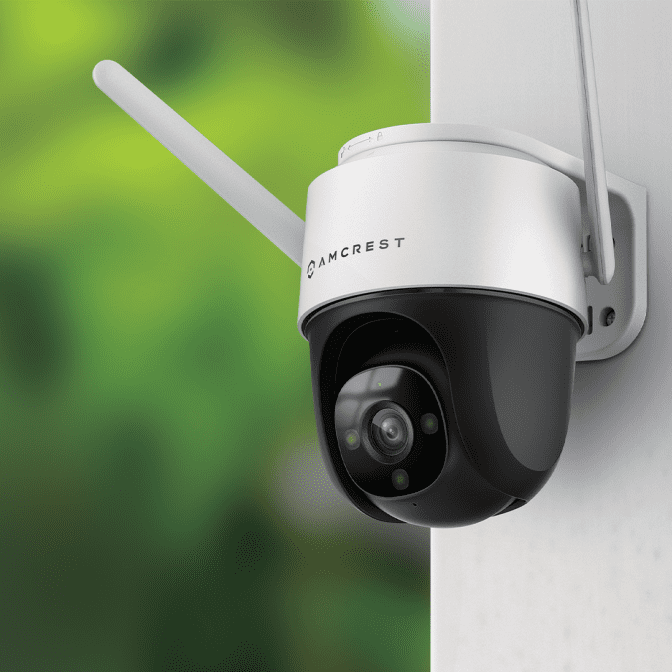 Outdoor security camera with antenna mounted on white wall.
